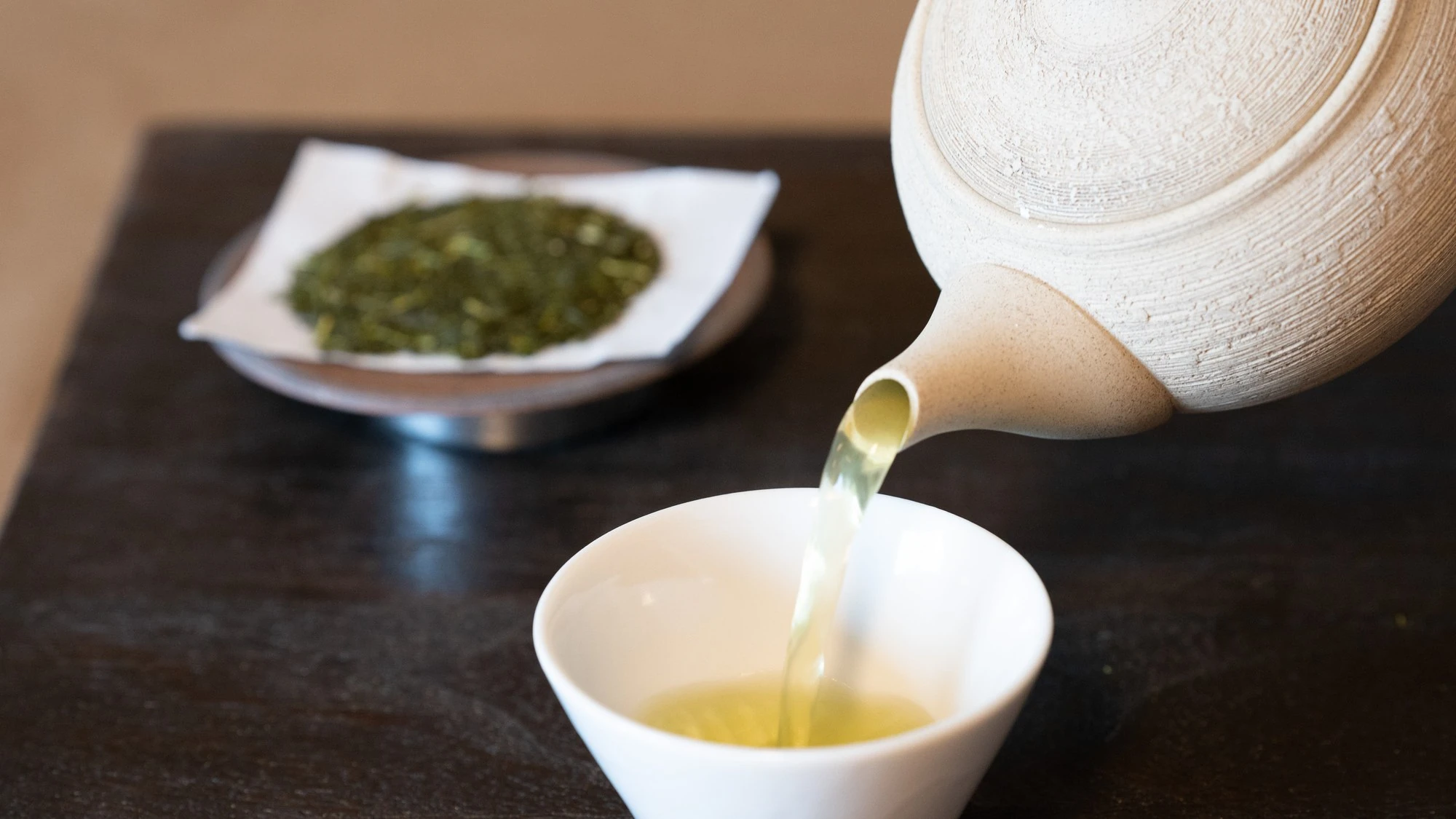 急須から湯呑みに緑茶を注いでいる様子